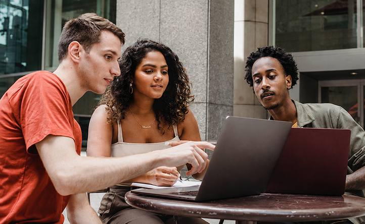 Three people collaborating around a laptop