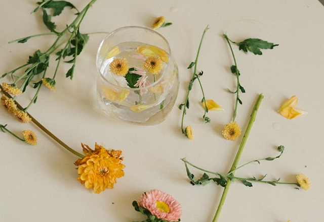 Yellow and pink flowers arranged around a glass vase